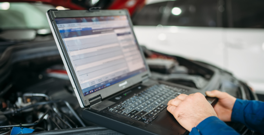 Diagnostyka samochodu z użyciem laptopa podczas ustalania przyczyny usterki pojazdu.